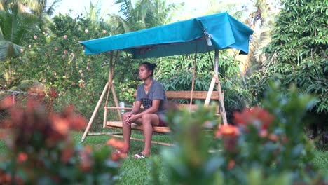 lonely and sad filipina orphan girl sitting on a swing chair at the orphanage home in the philippines - low angle shot