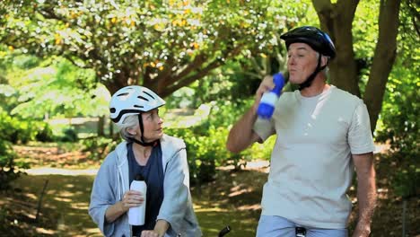 elderly couple drinking and biking