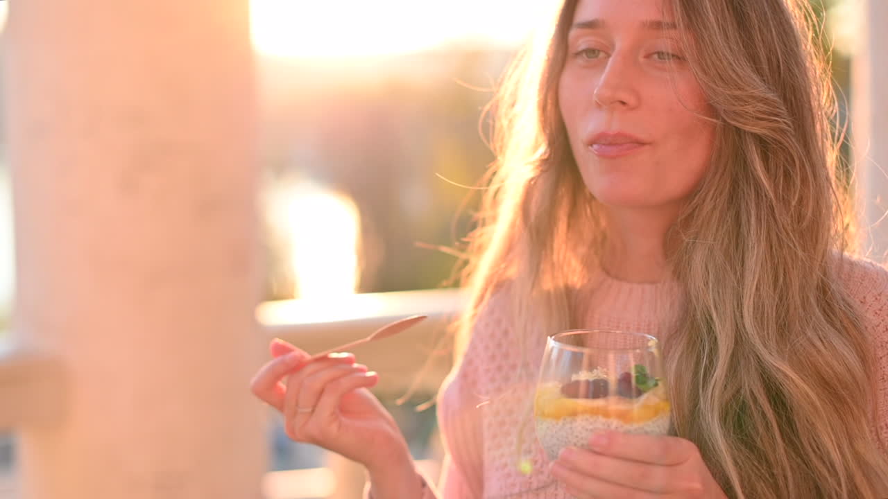 Donna che mangia una macedonia con semi di chia in un parco al tramonto
