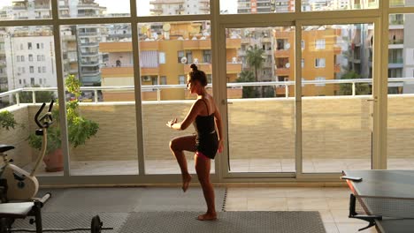 mujer practicando yoga en un balcón con vista a la ciudad