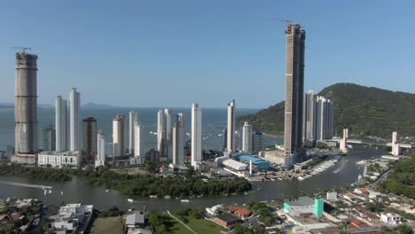 boats sailing on camboriú river with cityscape towers and skyscrapers at background in southern brazil