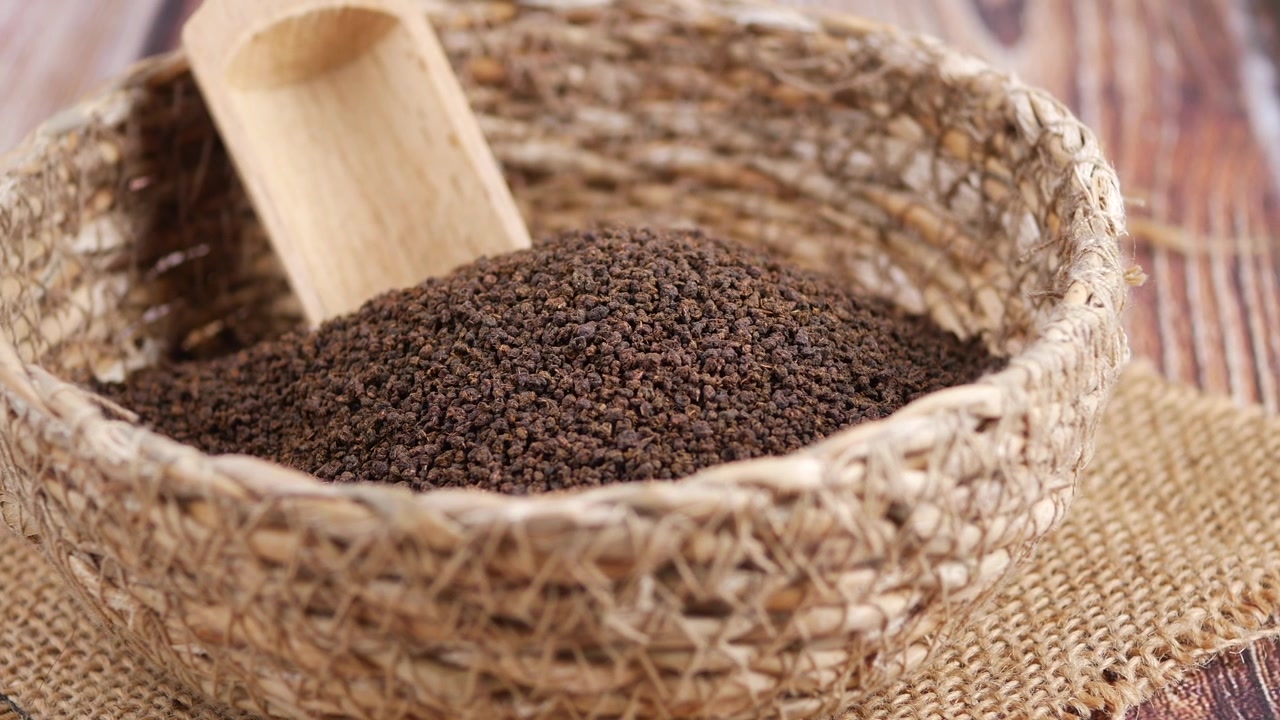 Dried Tea Leaves in a Woven Basket with Wooden Scoop