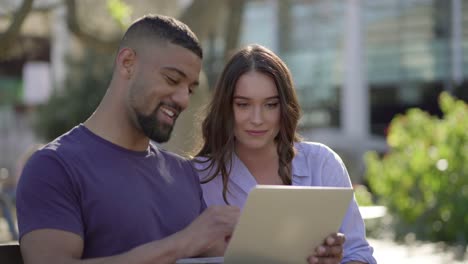 man showing woman something on laptop, both looking involved