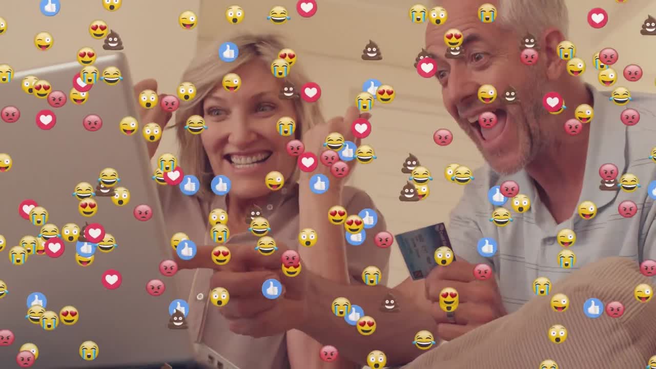 animación de emoji facial sobre pareja de adultos mayores caucásicos con tarjeta de crédito celebrando mirando la computadora portátil.