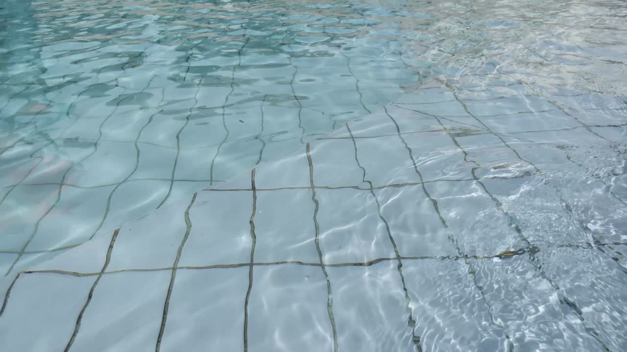 Vandoverflade i swimmingpool. Skinnende blå vandkrusningsbaggrund. Tropisk vandbaggrund. Video 4k