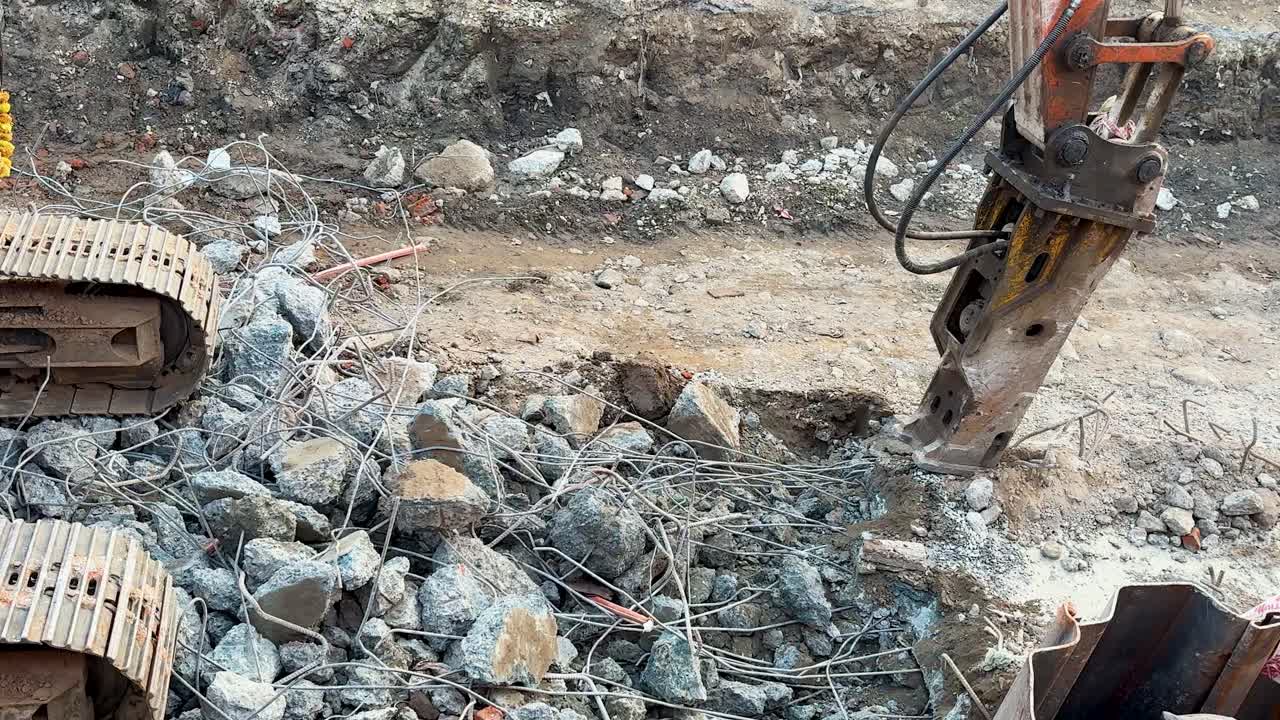 Lavori di riparazione delle infrastrutture con martello idraulico che rompe il cemento in un'area di scavo