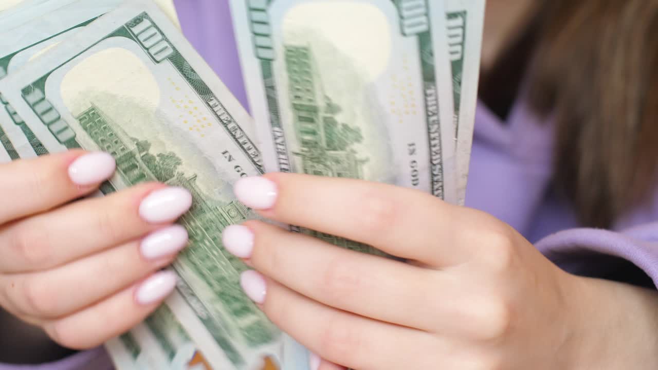 Closeup of dollar banknotes in female hands with manicure.Woman counts cash dollars holding in her hands.Family budget concept. Selective focus. American currency bills