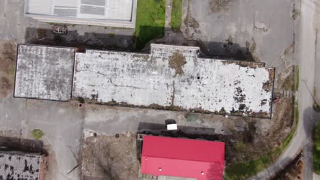 top down rotating drone footage of a large abandoned building with a decaying, overgrown roof