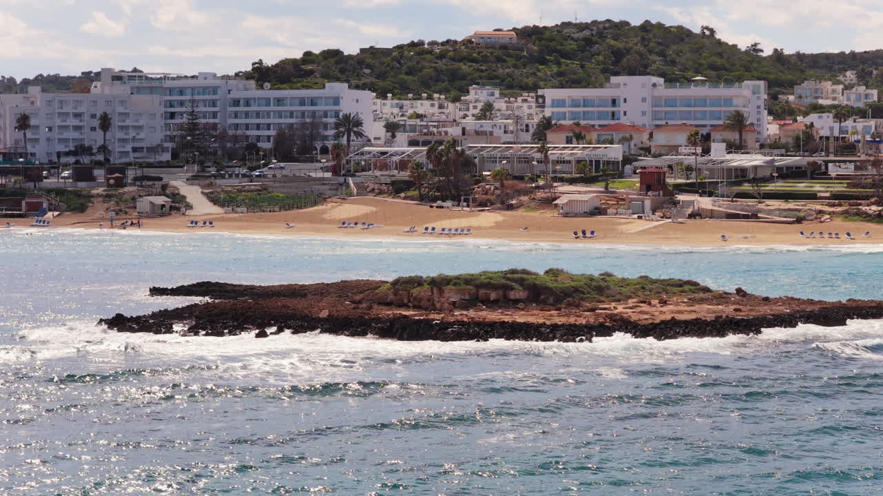 Vista aerea con drone di un piccolo isolotto roccioso circondato dalle onde al largo della costa di Protaras, spiaggia di Fig Tree, Cipro