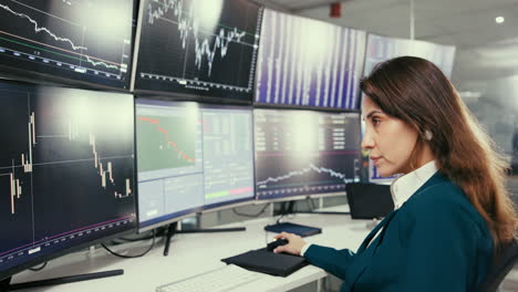 businesswoman analyzing financial data on multiple computer monitors