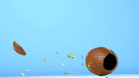 animación de confeti dorado cayendo sobre el huevo de pascua de chocolate cayendo y rompiéndose, en azul