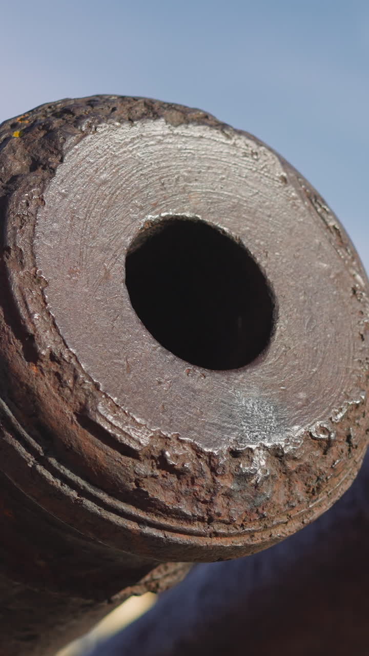 Old cannon tubes and muzzles covered with rust against blue sky with white clouds. Rusty military equipment made for warfare exhibited on sunny day closeup