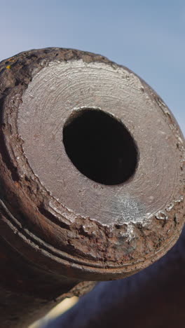 old cannon tubes and muzzles covered with rust against blue sky with white clouds. rusty military equipment made for warfare exhibited on sunny day closeup