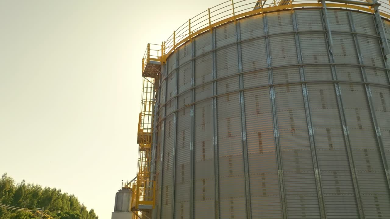 deslizamiento derecho tiro silos comerciales de grano con el sol en el fondo y la revelación de los rayos del sol almacenamiento de acero para la cosecha agrícola