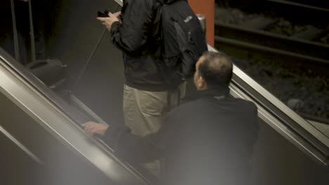 people ride an escalator in a dimly lit subway station