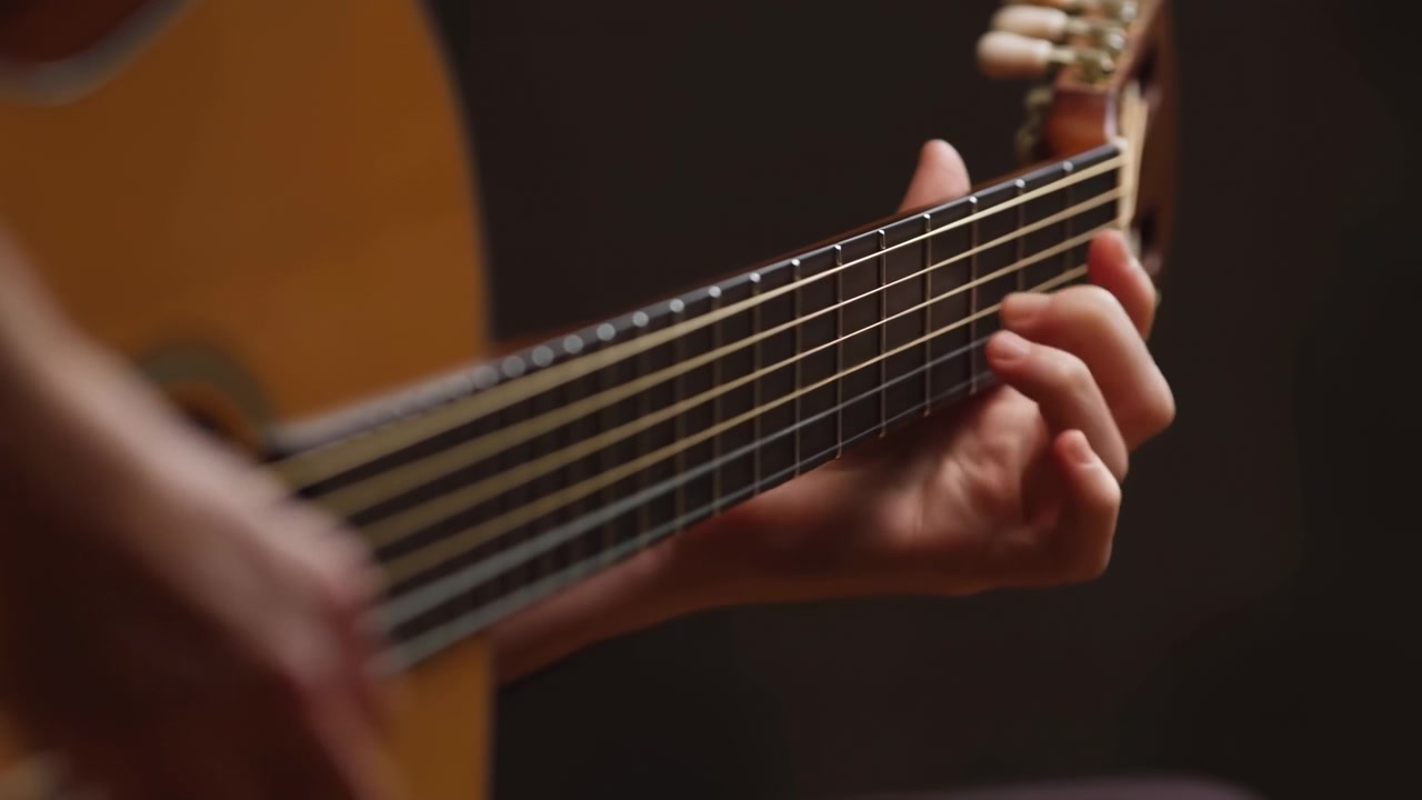 Primo piano ravvicinato di una mano sinistra sul manico di una chitarra acustica, dita che premono corde d'acciaio sui tasti scuri con il corpo in legno lucido che si intravede dolcemente