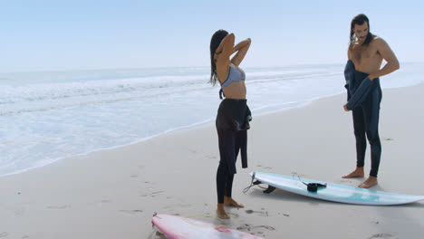 surfer couple removing their wetsuits 4k