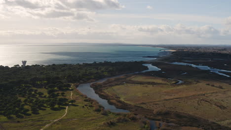 River-with-wetlands-and-pine-trees-around-going-into-mediterranean-sea-aerial