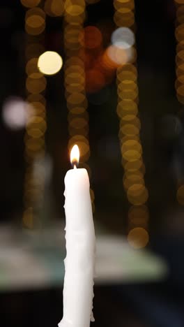 burning white candle with bokeh lights