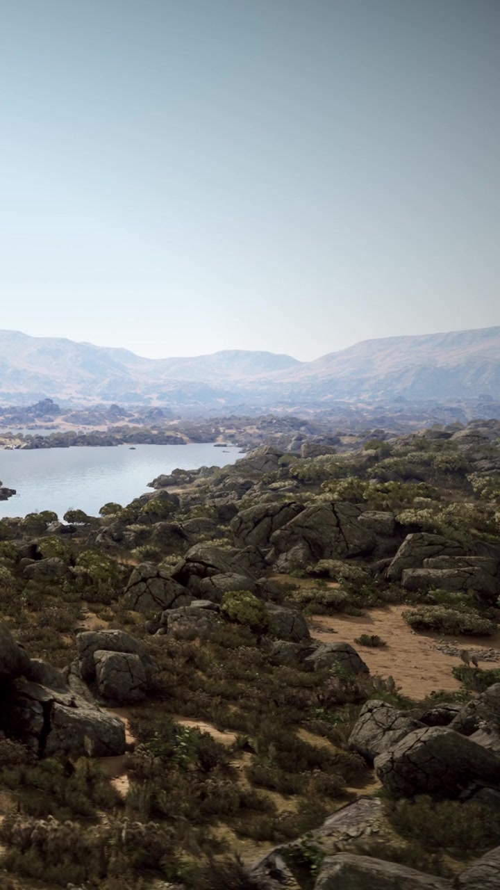 Vista de un lago rodeado de rocas y colinas con la luz de la tarde.