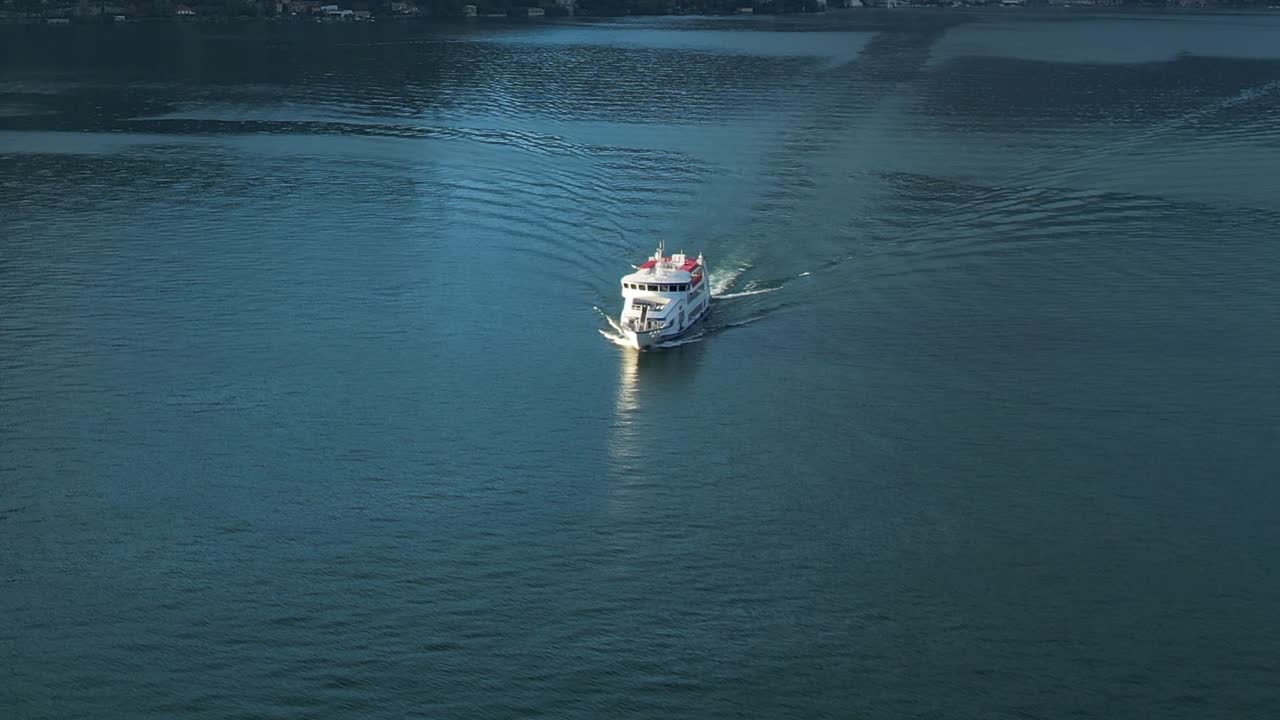 Drone view shows a boat gliding across the serene waters of the Alps