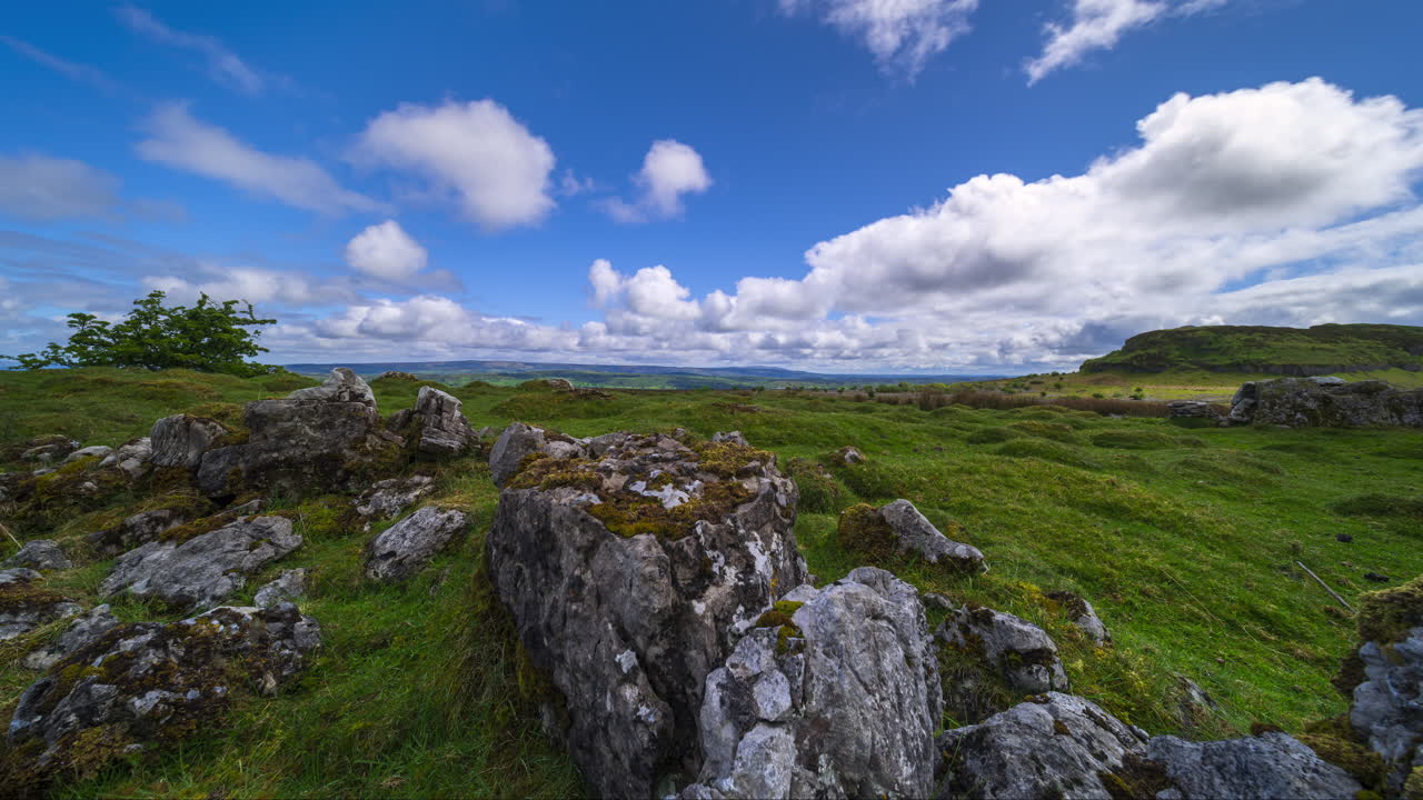 Timelapse af et landligt landskab med en klippeformation i forgrunden og bakker i det fjerne på en solrig og skyet dag, set fra Carrowkeel i County Sligo i Irland