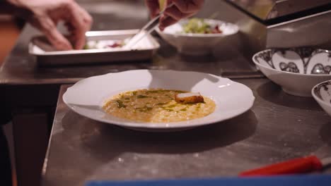 cocinero en un restaurante pone los trozos de pollo frito en el plato blanco con pasta