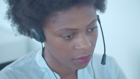 focused african american employee in headset taking call