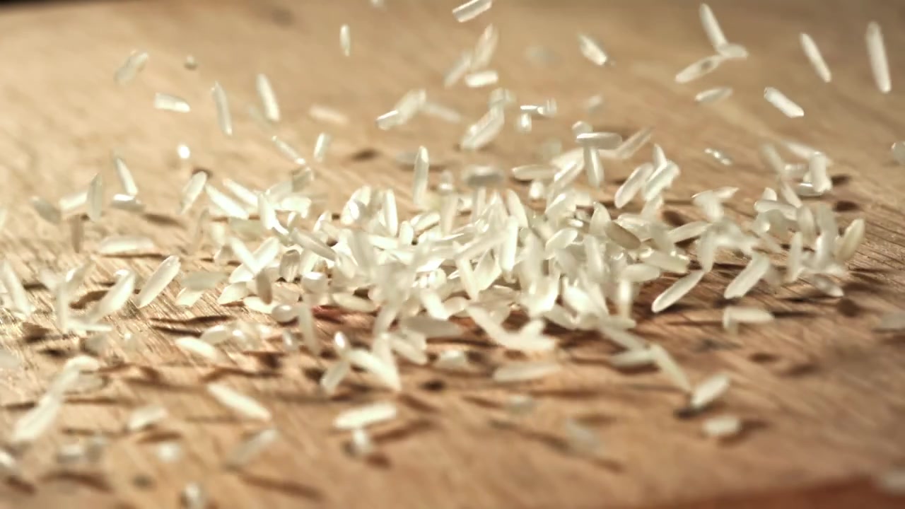 Rallentatore di chicchi di riso che cadono su una superficie di legno.