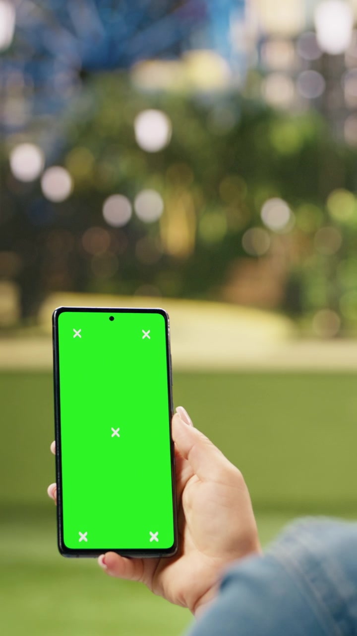 Video verticale. Mockup verticale isolato con schermo verde su smartphone tenuto da una donna.