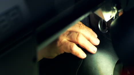 Leatherworker-stitching-black-leather-workpiece.-Close-up-handicraftsman-hands