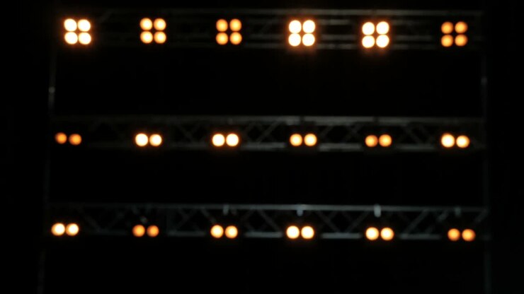 Blurred background of yellow lghts. Lights on the black stage.