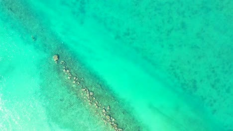 Türkisblaue-Meeresoberfläche-Mit-Ruhigem,-Klarem-Wasser-über-Wunderschönem-Meeresboden-Mit-Kieselsteinen-Und-Sand-Auf-Den-Turks--Und-Caicosinseln