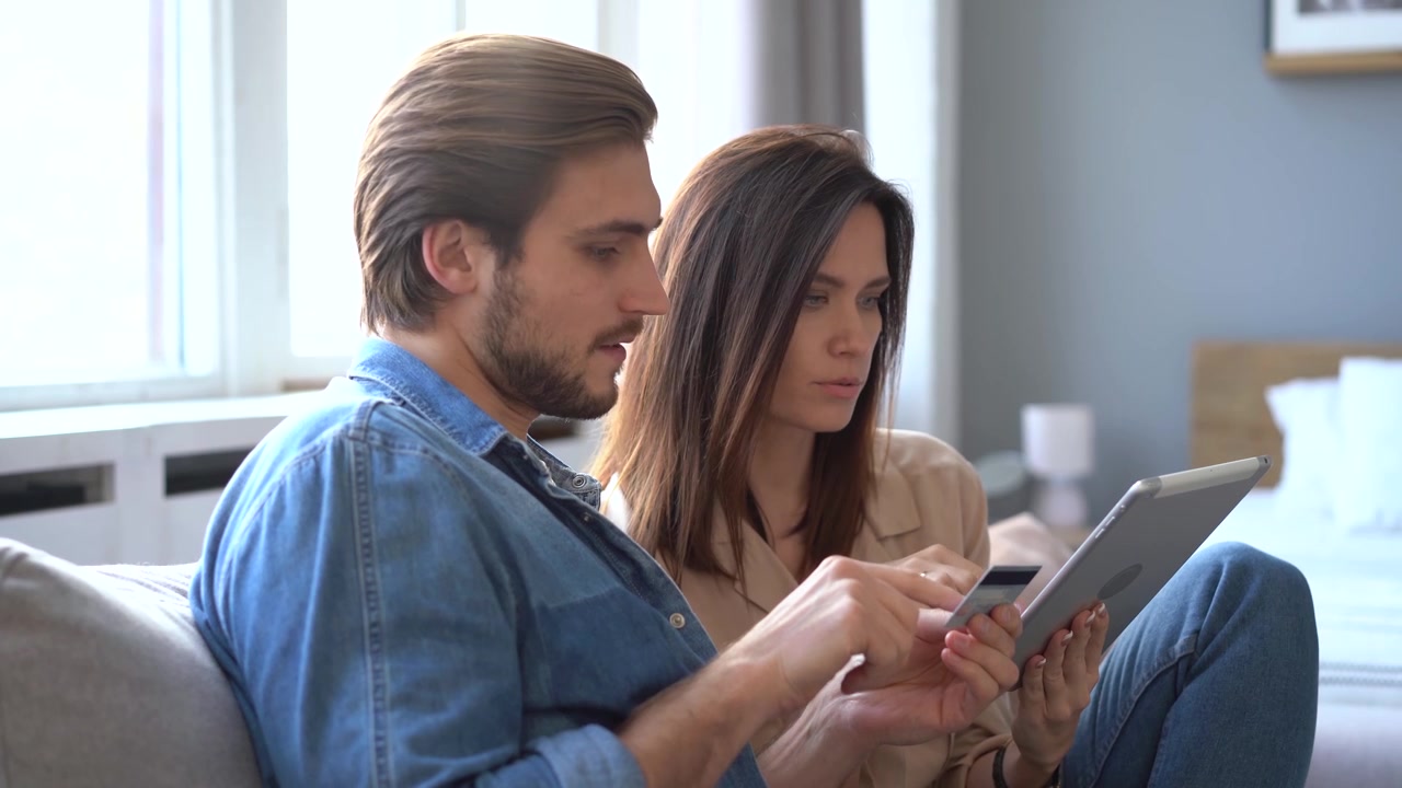 Ungt par, der handler online med tablet og kreditkort derhjemme