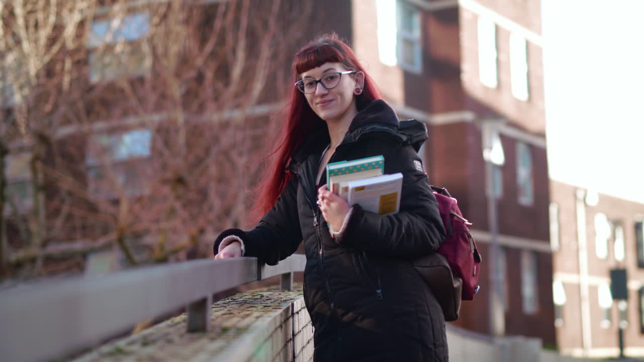 student stood on bridge turns to camera and smiles