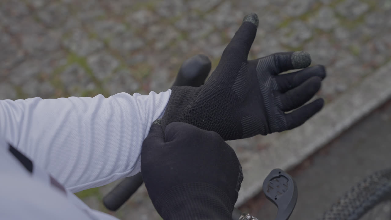 Nærbillede af en cyklist, der justerer handsken på hånden nær cykelstyret.