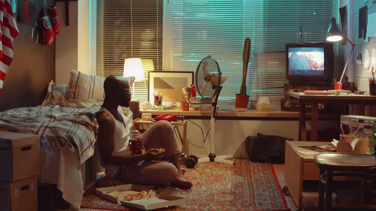 피자를 먹고 집에서 tv를 보는 아프리카계 미국인