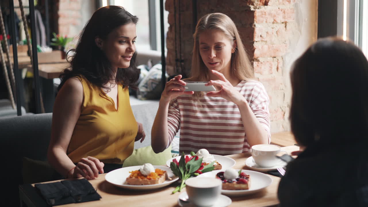 Friends taking a picture of dessert in cafe