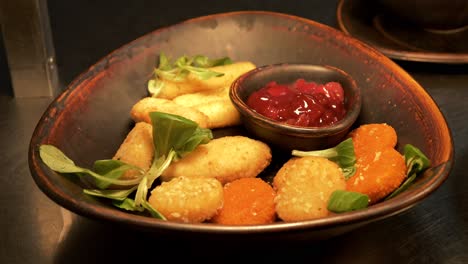 a platter with chicken nuggets, fresh herbs, and ketchup in a container