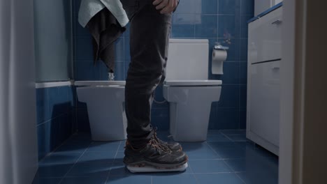 man weighing himself in a bathroom