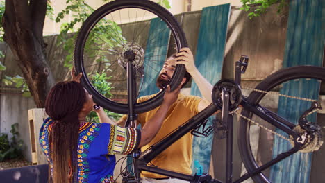 Multiracial-couple-maintains-bike-wheels