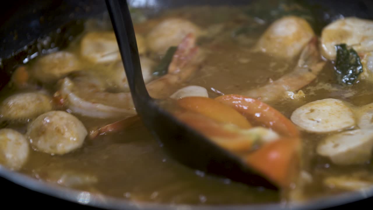 cocinando una clásica sopa picante thai tom yum con camarones, champiñones y tomate