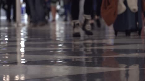 Low-angle-view-of-legs-in-crowds-walking-down-an-airport-terminal-on-Dec-26th,-one-of-the-busiest-flight-days