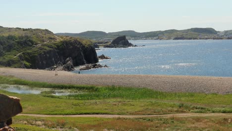 Tourist-hiking-along-a-rocky-shoreline-with-brisk-wind-on-the-water