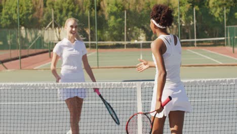 video of happy diverse female tennis players holding rackets and shaking hands