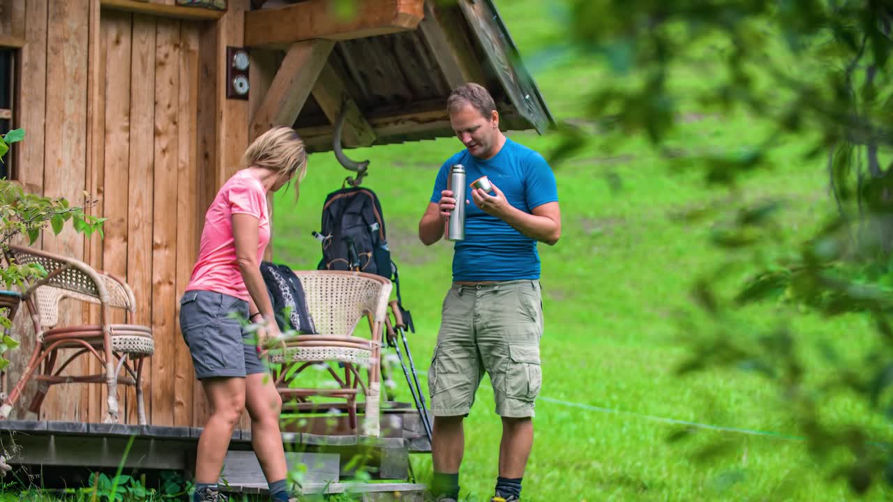 Couple taking a rest after a hike and drink a coffee enjoying the landscape mountain view. Topla Valley, Slovenia