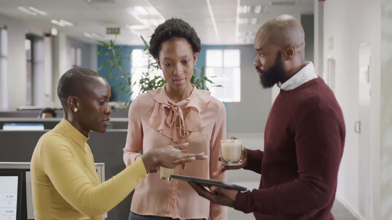 African american male and female colleagues discussing and having coffee in office, slow motion