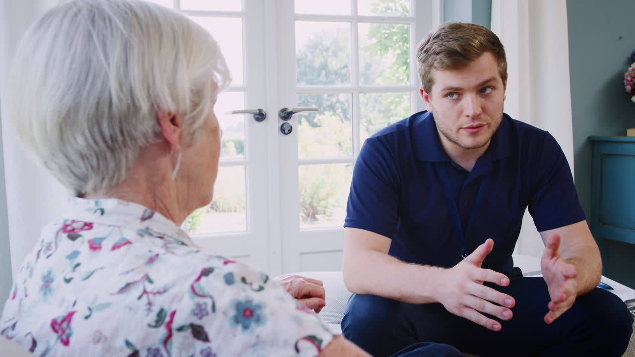 Senior woman talking with male care worker on home visit