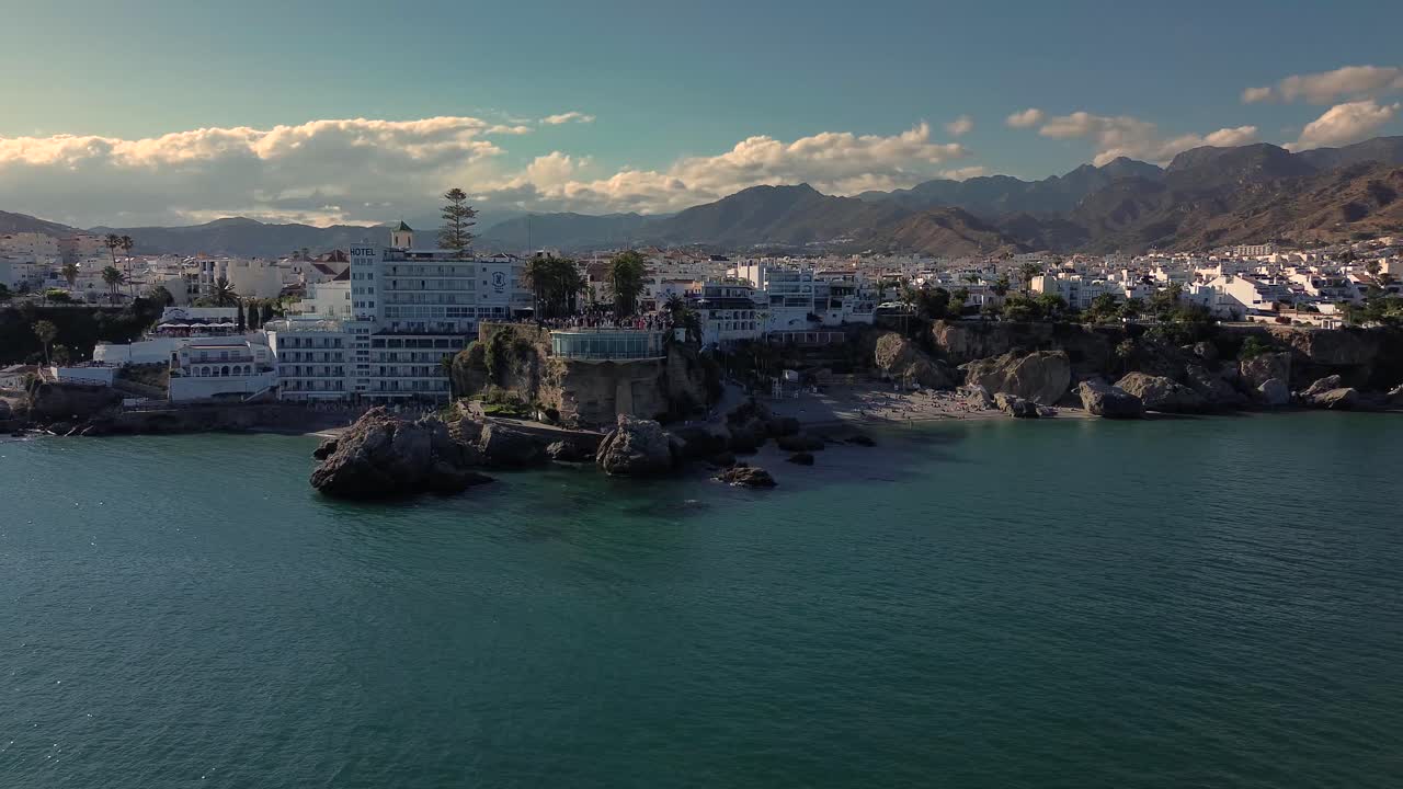 aerial drone footage of Nerja, a picturesque coastal town in southern Spain, captured on a clear afternoon with beautiful weather.