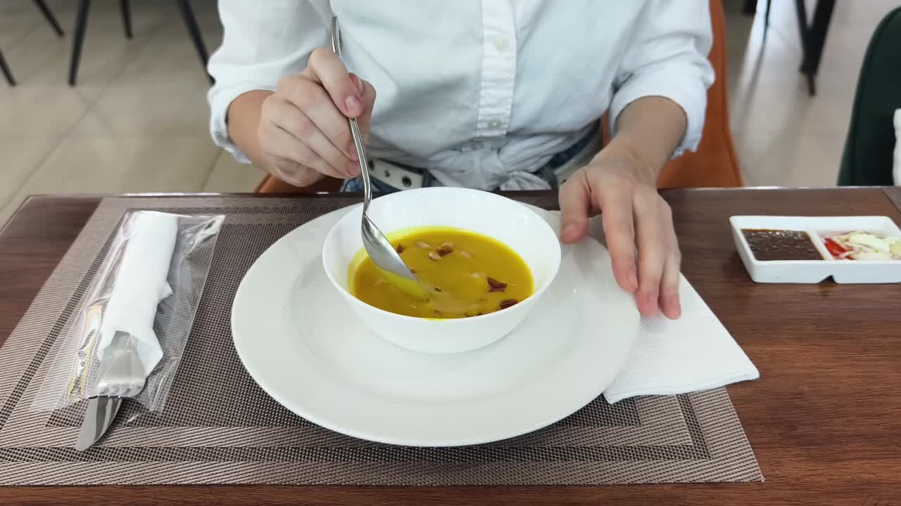 mujer comiendo sopa en un restaurante